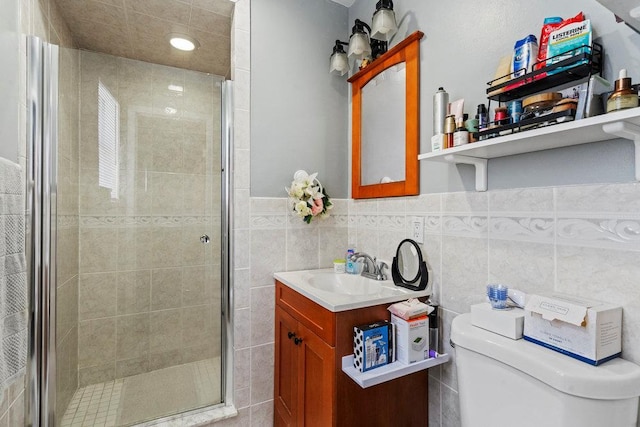 bathroom featuring vanity, toilet, a shower with shower door, and tile walls