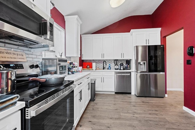 kitchen featuring tasteful backsplash, stainless steel appliances, light hardwood / wood-style flooring, white cabinetry, and lofted ceiling