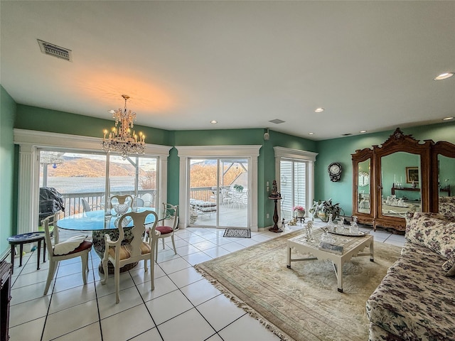 living room with light tile patterned floors, a water view, and an inviting chandelier