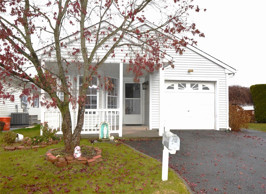 view of front of home featuring central AC, a front lawn, covered porch, and a garage