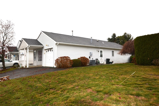 back of house featuring central air condition unit, a garage, and a lawn