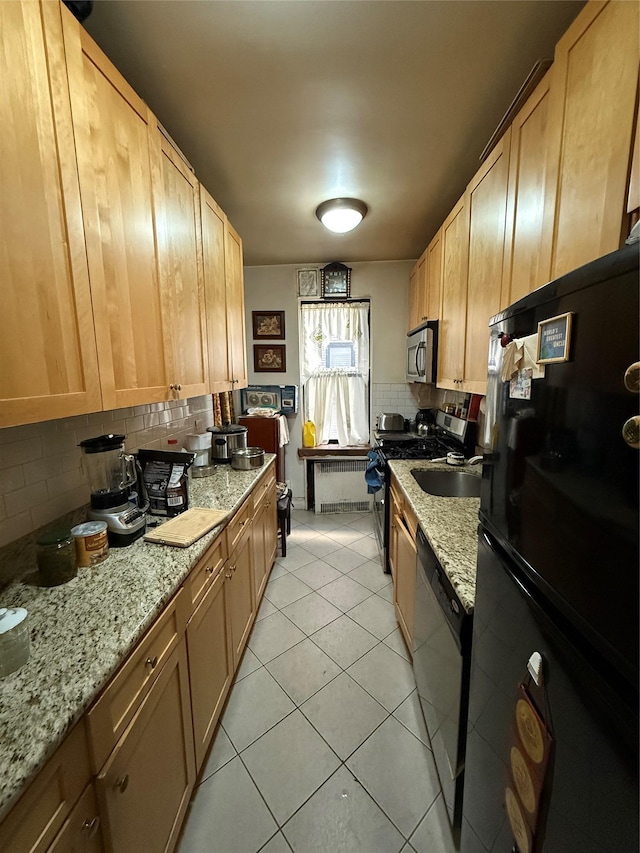 kitchen featuring radiator, light stone counters, backsplash, light tile patterned flooring, and appliances with stainless steel finishes