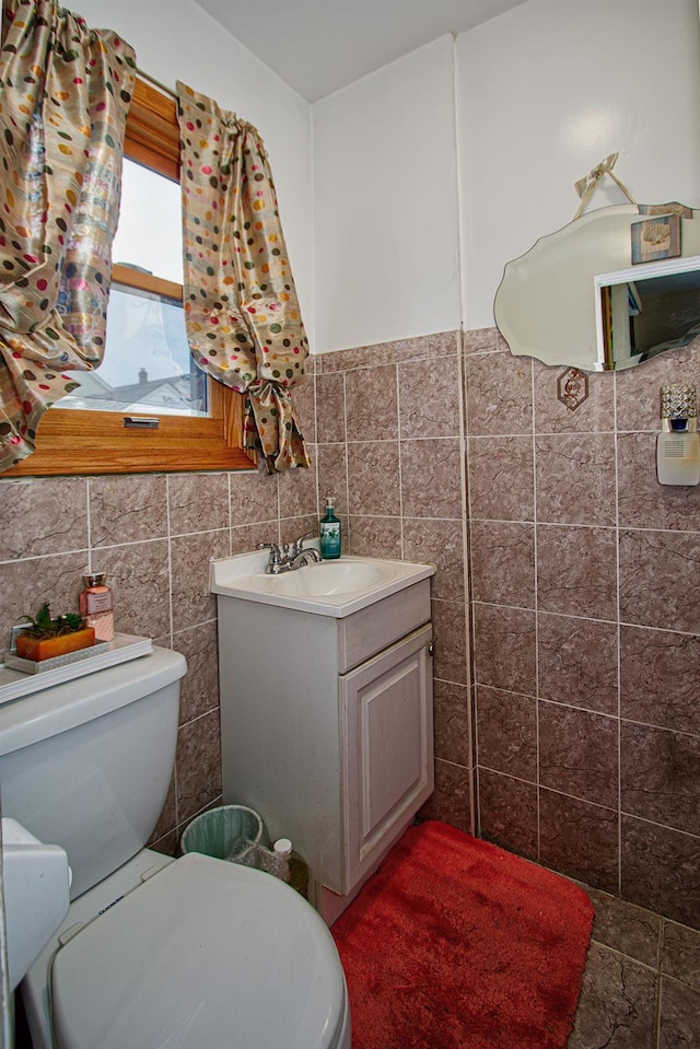 bathroom featuring toilet, tile walls, and vanity