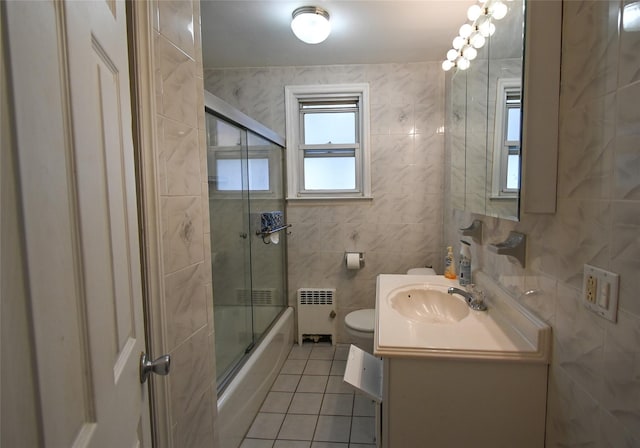 full bathroom with combined bath / shower with glass door, radiator, tile walls, tile patterned flooring, and toilet