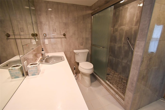 bathroom featuring tile patterned floors, toilet, vanity, a shower with shower door, and tile walls