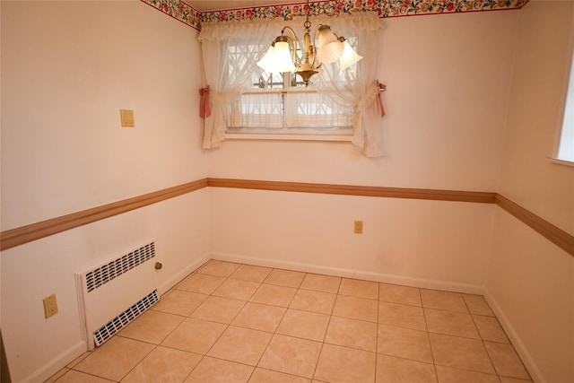 spare room featuring a notable chandelier and radiator