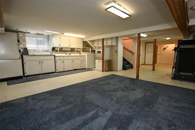 kitchen with white appliances, sink, light colored carpet, white cabinetry, and washer / clothes dryer