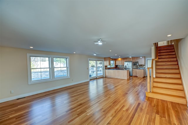 unfurnished living room featuring recessed lighting, visible vents, light wood-type flooring, baseboards, and stairs