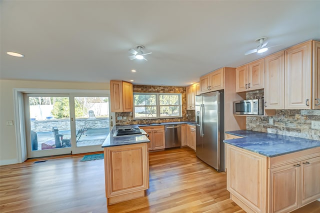 kitchen with stainless steel appliances, dark countertops, a sink, and a peninsula