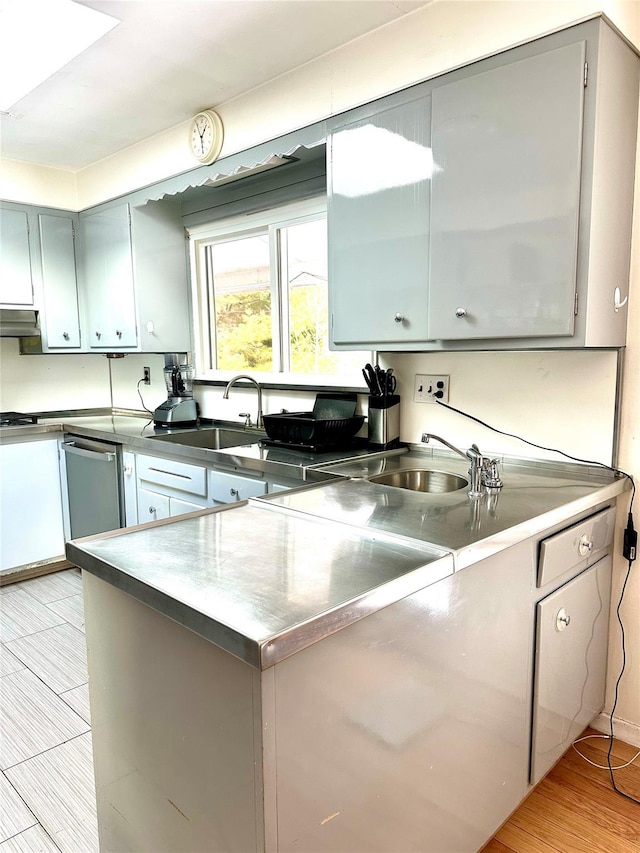 kitchen with gray cabinetry, sink, extractor fan, and light hardwood / wood-style floors