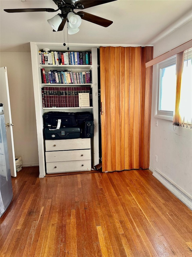 unfurnished bedroom featuring ceiling fan, wood-type flooring, and baseboard heating