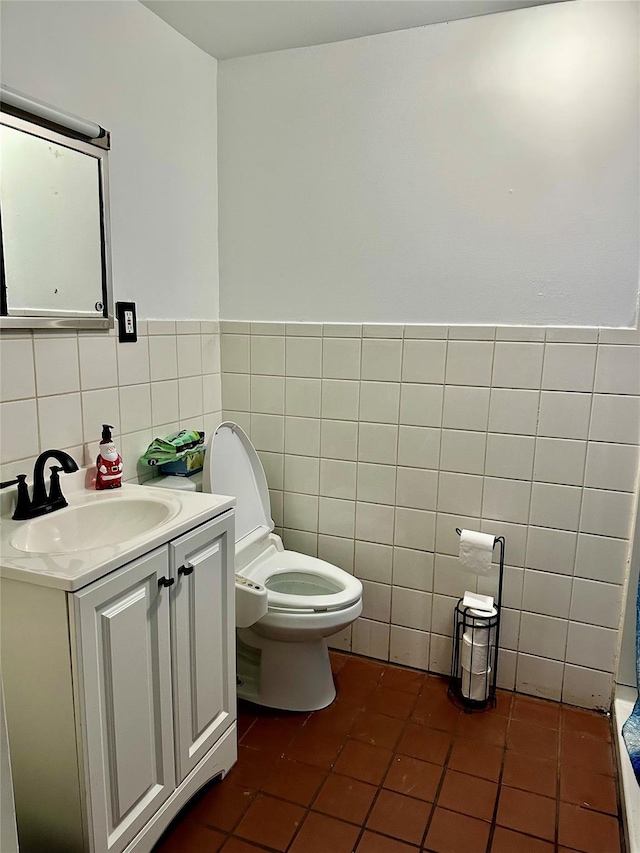 bathroom with tile patterned flooring, vanity, toilet, and tile walls