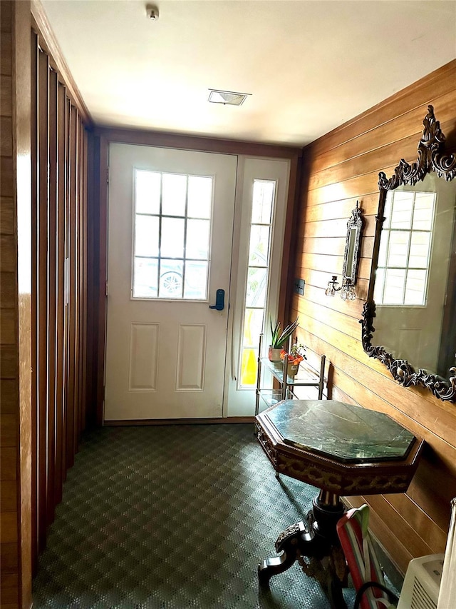 doorway featuring wood walls and carpet