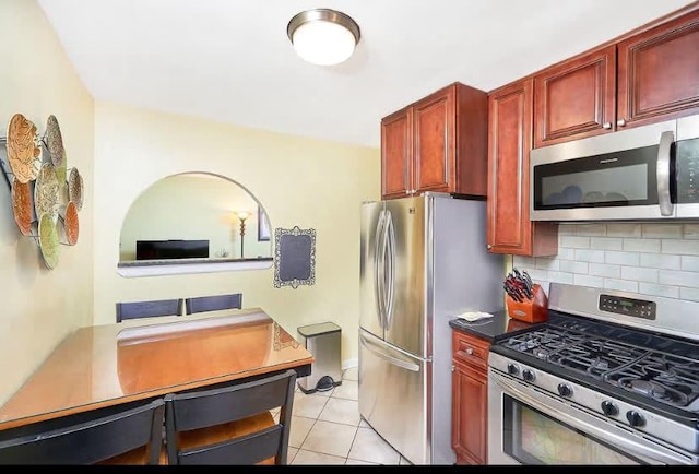 1165 E 54th St Unit 3S, Brooklyn, NY 11234 - kitchen with appliances with stainless steel finishes, reddish brown cabinets, backsplash, light tile patterned flooring, and an office area