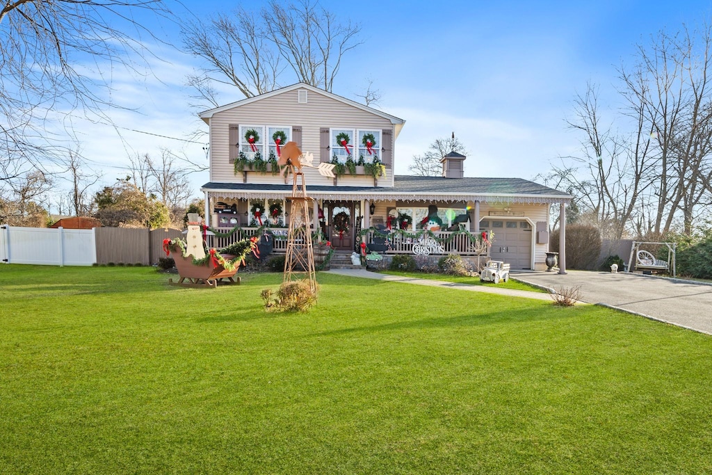 view of front of home featuring covered porch, a garage, and a front yard