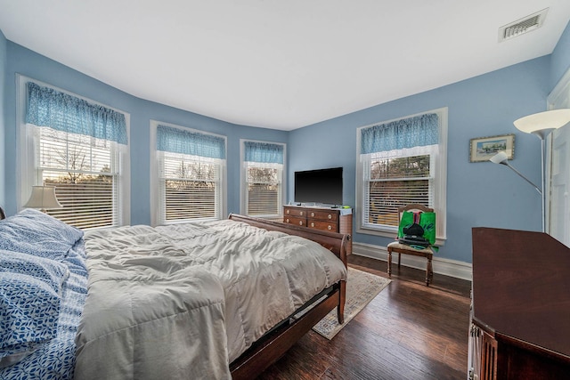 bedroom with dark hardwood / wood-style floors and multiple windows