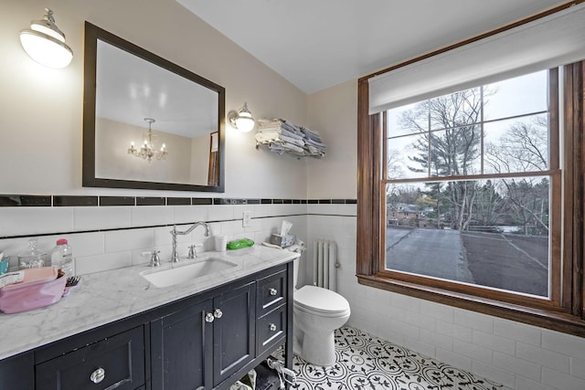 bathroom featuring radiator, an inviting chandelier, tile patterned floors, toilet, and tile walls