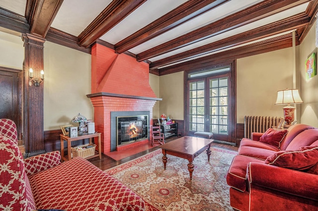 living room featuring radiator, crown molding, hardwood / wood-style flooring, beamed ceiling, and a fireplace