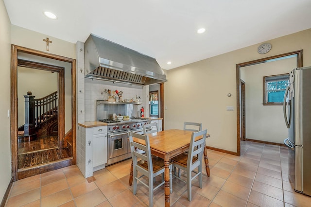 kitchen with stainless steel appliances, white cabinets, extractor fan, and light tile patterned floors