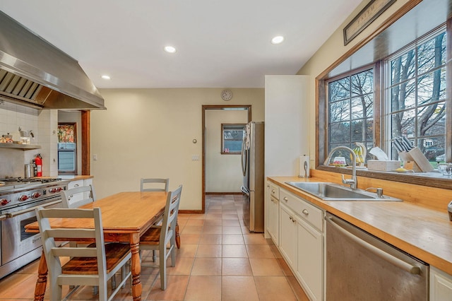 kitchen with ventilation hood, sink, decorative backsplash, light tile patterned floors, and stainless steel appliances