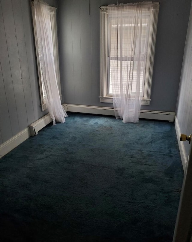 empty room featuring dark colored carpet and wooden walls