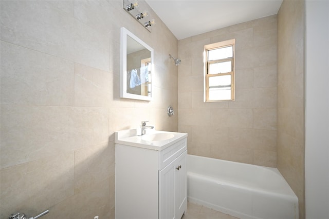 bathroom featuring vanity, tiled shower / bath combo, and tile walls