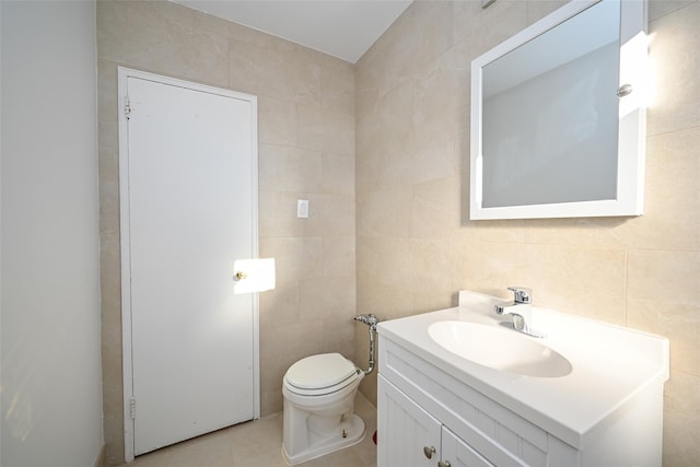 bathroom featuring tile patterned floors, vanity, toilet, and tile walls