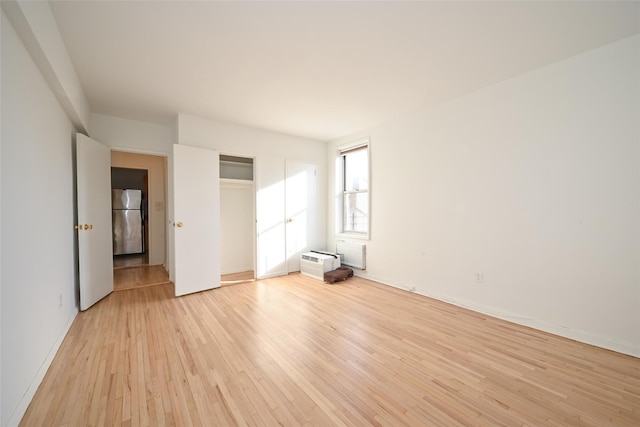 unfurnished bedroom featuring stainless steel refrigerator, a closet, and light hardwood / wood-style flooring