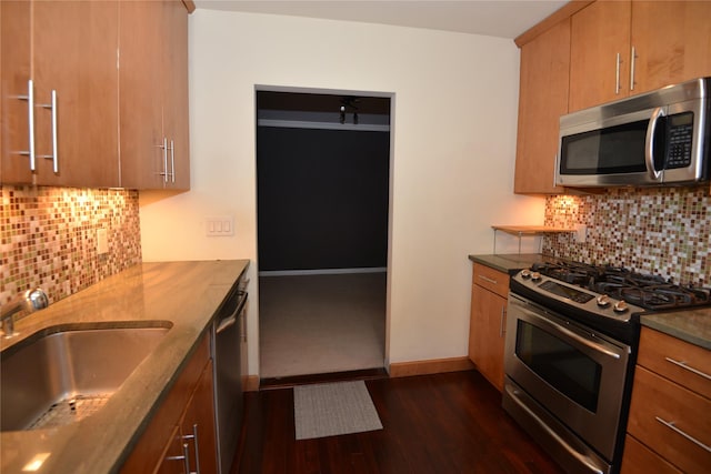 kitchen with appliances with stainless steel finishes, tasteful backsplash, dark wood-type flooring, and sink