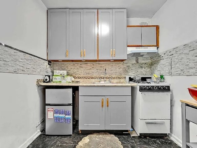 kitchen featuring sink, white range, stainless steel fridge, gray cabinets, and decorative backsplash