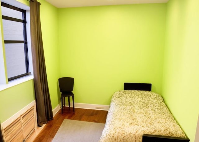 bedroom featuring multiple windows and dark hardwood / wood-style flooring