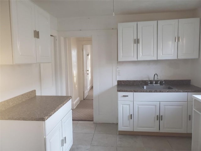 kitchen featuring white cabinets, light tile patterned flooring, and sink