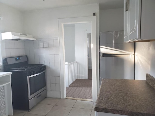 kitchen featuring appliances with stainless steel finishes, light tile patterned floors, extractor fan, and tile walls