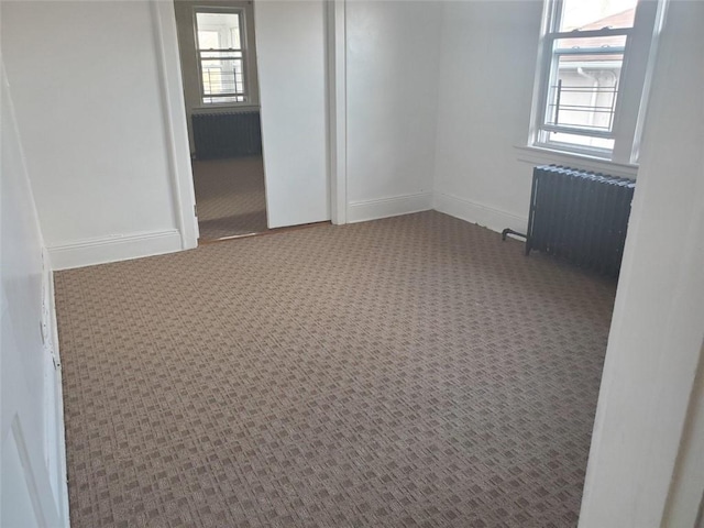 empty room featuring carpet and radiator heating unit