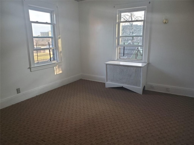 carpeted empty room featuring radiator heating unit