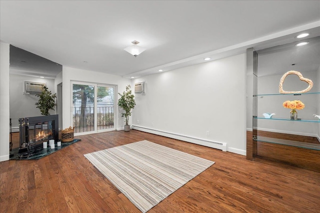 living area with wood-type flooring, baseboard heating, and a wall mounted AC