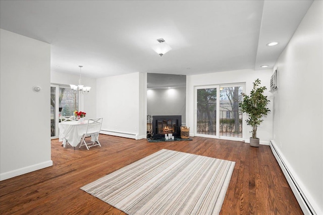 unfurnished living room with baseboard heating, dark hardwood / wood-style flooring, and an inviting chandelier