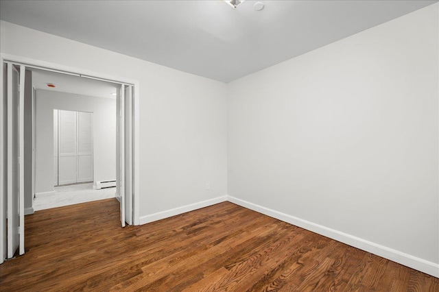 spare room with a baseboard radiator and wood-type flooring