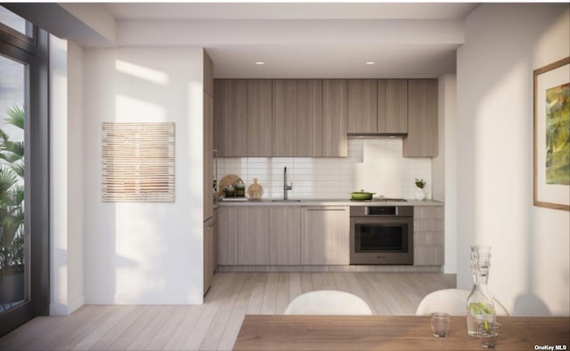 kitchen featuring backsplash, sink, stainless steel appliances, and light hardwood / wood-style flooring