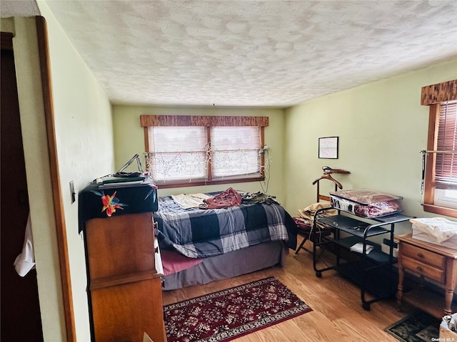 bedroom with a textured ceiling and light wood-type flooring