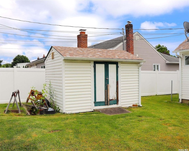 rear view of house featuring a yard and a shed