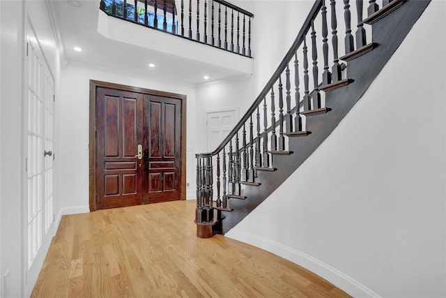 foyer entrance featuring light hardwood / wood-style floors, a high ceiling, and ornamental molding