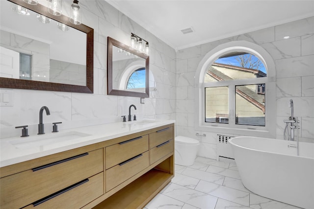 bathroom with a tub to relax in, vanity, tile walls, radiator heating unit, and toilet