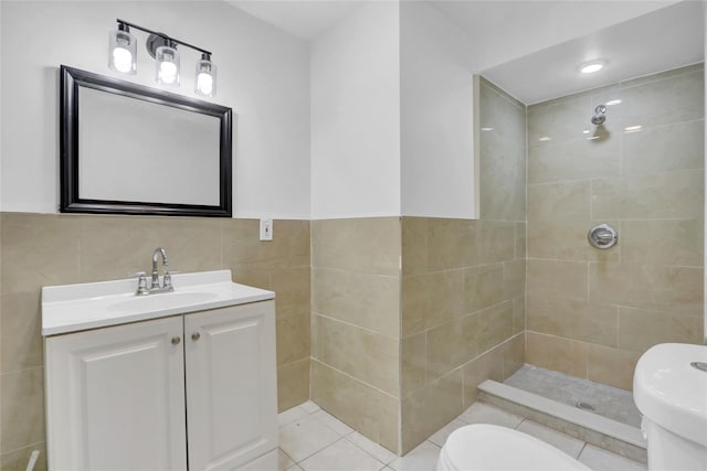 bathroom with vanity, tiled shower, tile walls, tile patterned flooring, and toilet