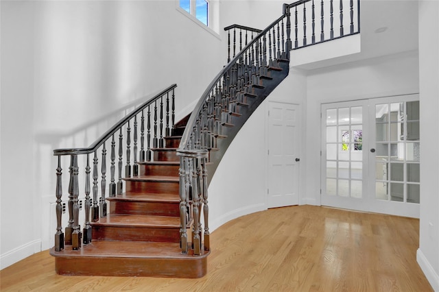 stairway featuring hardwood / wood-style floors, a high ceiling, and french doors