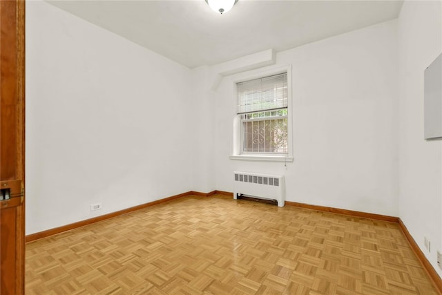 spare room featuring radiator and light parquet floors