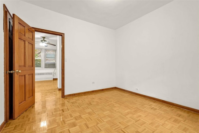 unfurnished room featuring ceiling fan, radiator heating unit, and light parquet flooring