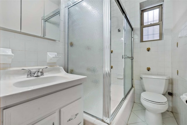 full bathroom with tile patterned flooring, toilet, tile walls, and shower / bath combination with glass door