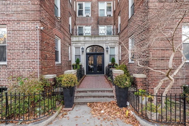 view of exterior entry featuring a balcony and french doors