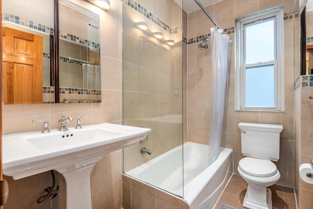 full bathroom with shower / bath combo, toilet, tile walls, and a wealth of natural light